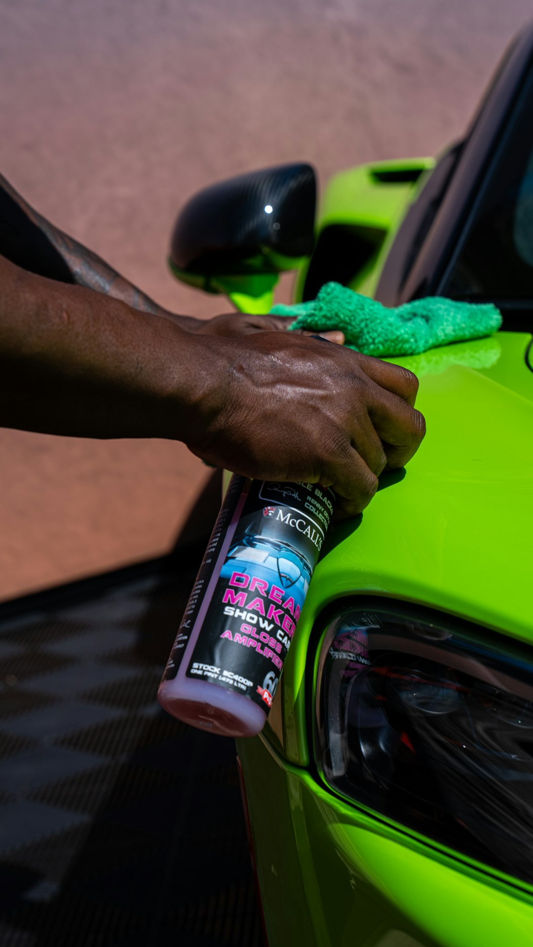 a person cleaning a green car with a sponge