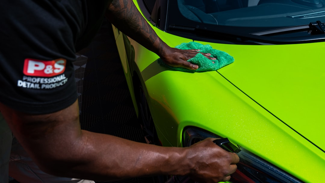 man polishing the side of a green sports car